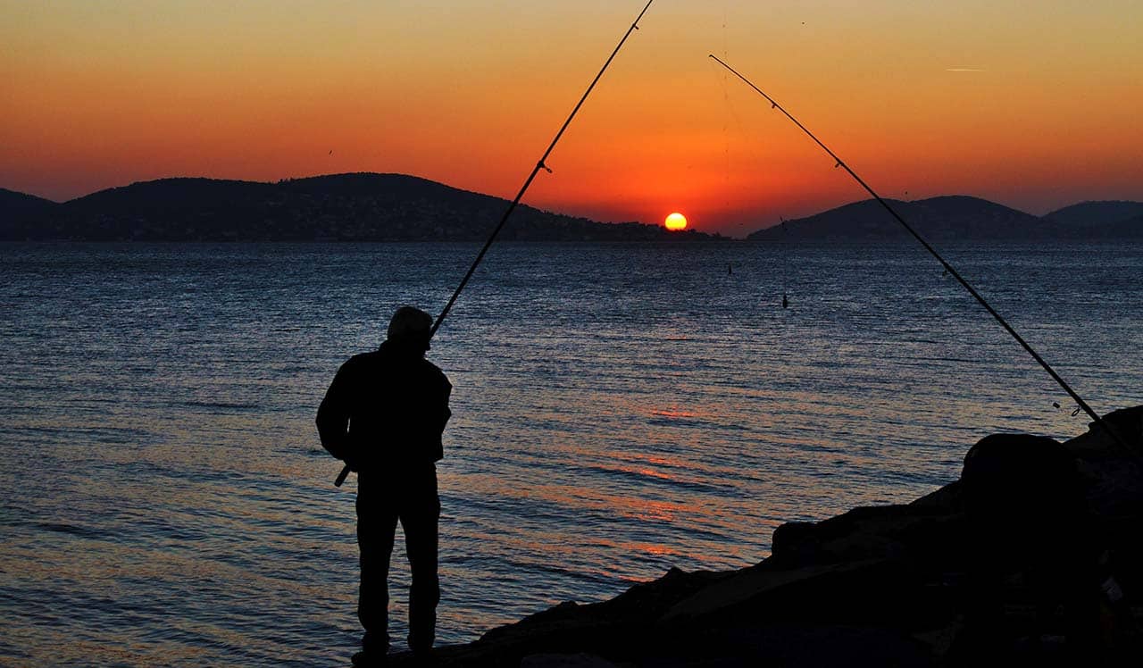 homem pescando ao pôr do sol